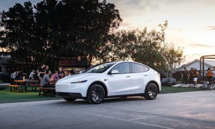White Tesla Model Y parked at outdoor evening event with people