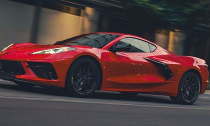 A red 2026 Corvette Stingray speeds down a city street at dusk. Motion blur highlights its aerodynamic design, reflecting a sense of power and excitement.