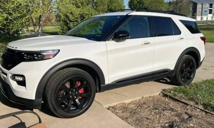 White Ford Explorer with black accents and wheels parked on suburban street with trees and grass