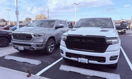 Two parked RAM 1500 trucks in a dealership lot on a clear day. One is silver and the other is white. Their bold grilles and large frames convey strength.