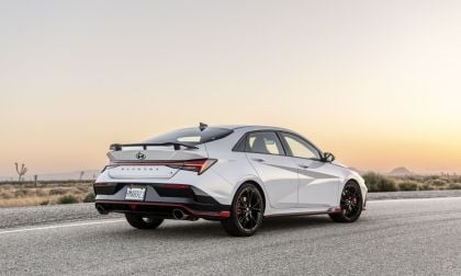 A 2025 White Hyundai Elantra N with sporty red accents and black rims is parked on a desert road at sunset, evoking a sense of adventure and freedom.