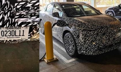 A camouflaged car with a Tennessee manufacturer plate is parked in a garage, partially visible alongside a charging station.