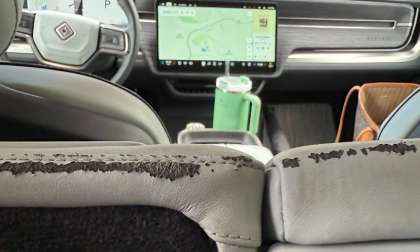 Close-up view of the rear seatback edge in Kate's 2023 Rivian R1S showing peeling upholstery material and surface degradation along a stitched section of the light-colored seat trim.
