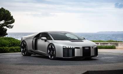 Silver Audi Nuvolari sports car parked near the coast with the ocean and cloudy sky behind it.  