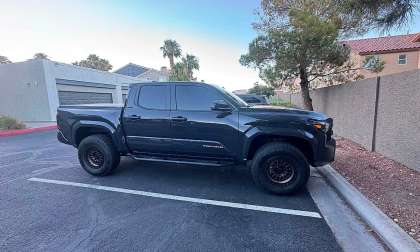 Black Toyota Tacoma shown in side profile parked in a residential parking lot.