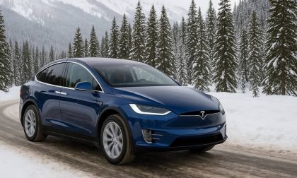Blue Tesla Model X driving on a snow-covered mountain road