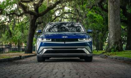Blue Hyundai Ioniq 5 shown from the front on an oak-lined brick street with hanging moss.