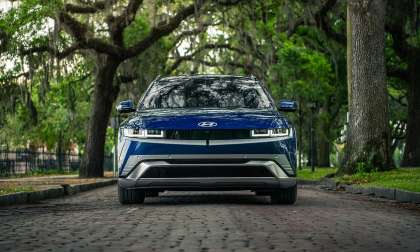 Blue Hyundai Ioniq 5 shown from the front on an oak-lined brick street with hanging moss.