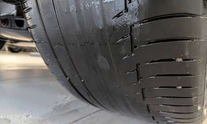 BMW tire with excessive uneven wear exposing a nearly bald inner shoulder despite tread remaining on the outer edge.