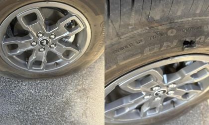Flat tire with visible wheel rim damage and puncture, showing tire sidewall and alloy wheel details