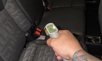 Hand using infrared thermometer measuring temperature of car seat