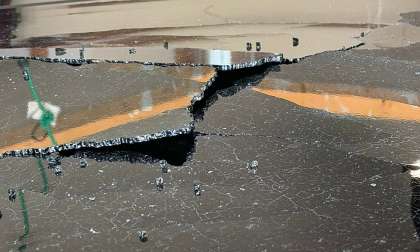 Detailed view of the panoramic glass roof on Carrie's 2025 Kia Telluride showing a significant crack running through the panel, with shattered edges and multiple stress fractures extending across the glass surface.