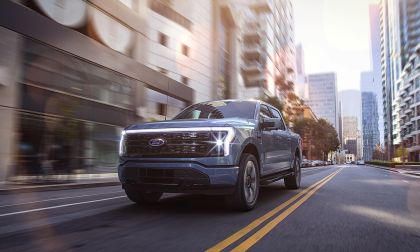Ford F-150 Lightning electric pickup truck driving through a modern city street.