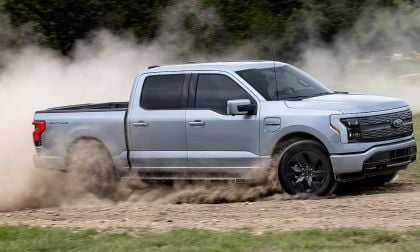 Silver Ford F-150 Lightning Lariat electric pickup truck sideways on dirt rally course with large dust cloud