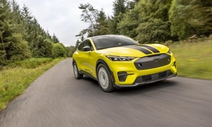 Yellow Ford Mustang Mach-E Rally electric SUV kicking up dust while driving on a gravel dirt road