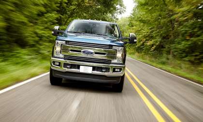 Silver Ford F-150 Lightning driving on a dusty off-road trail.