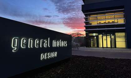Exterior of GM Design Studio UK with illuminated General Motors Design sign at sunset.