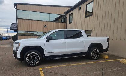 White GMC Sierra EV parked in lot side profile view