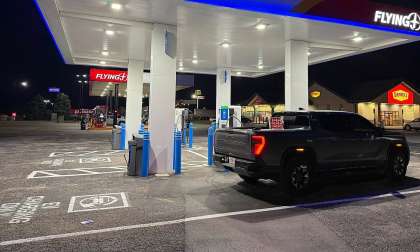 GMC Sierra EV parked at a GM Energy charging station at a Flying J travel center at night.