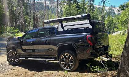 Gregg’s GMC Sierra EV Denali parked at a wooded campsite with overlanding gear mounted in the bed.