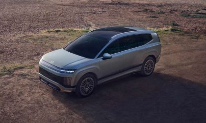 Aerial three-quarter view of a Hyundai IONIQ 9 electric SUV with a sleek gray exterior on a dirt overlook.
