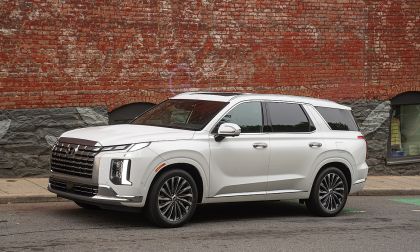 White Hyundai Palisade luxury SUV parked on a city street in front of a brick building.