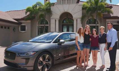 A family stands next to a Jaguar