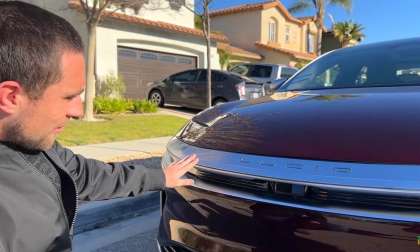 Image showing Kevin from the Meet Kevin YouTube channel crouching by the front of his Zenith red Lucid Air Dream Edition.