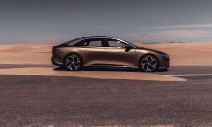 Image of a Eureka Gold Lucid Air Dream Edition in the desert of Saudi Arabia with sand blowing across the road.