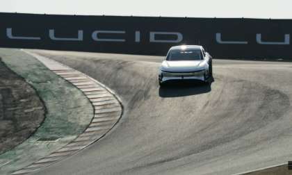 A prototype tri-motor Lucid Air enters the corkscrew corner at Laguna Seca, with Lucid bannering in the background.