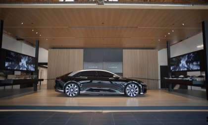 Image showing a dark red Lucid Air parked in the company's flagship Beverly Hills Studio. The dark red of the car contrasts with the light wood around it in the Studio.