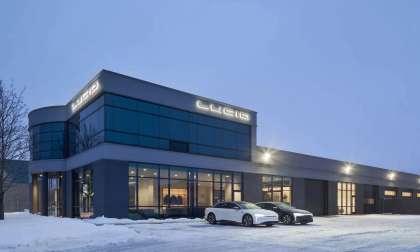 Image showing a pair of Lucid Airs parked outside Lucid's huge new combination Studio/Service Centre in West Montreal. The building looms large against the snow and steely grey sky, with the Lucid logo illuminated on two sides of the facade.