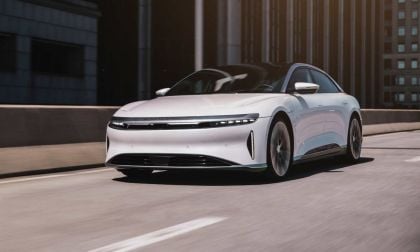 Image showing a white Lucid Air driving on an elevated highway through a city.
