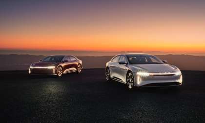 White and red examples of the Lucid Air are pictured parked on a hilltop at sunset.