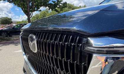 Close-up of scratches and paint damage on the front grille and hood edge of a Mazda SUV.