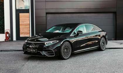 Black Mercedes-Benz EQS electric sedan parked in front of a modern garage.