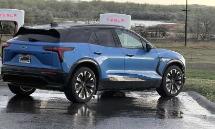 Michael's blue Chevrolet Blazer EV parked at a Tesla Supercharger station on a rainy day during a road trip.