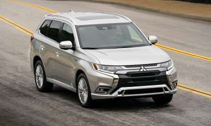 Silver Mitsubishi Outlander plug-in hybrid driving on a curving road.