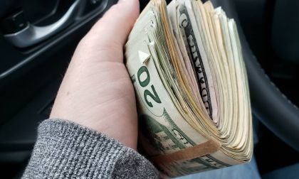 A car shopper holds a fat stack of bills in his hand
