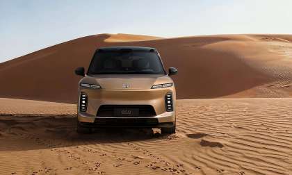 Gold Nio ES9 SUV shown from the front on desert sand dunes.