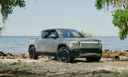 Rivian R1T parked on sandy beach with coastal trees