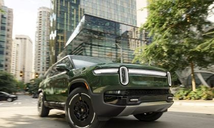 Rivian R1S electric SUV driving on highway with mountains and cloudy sky