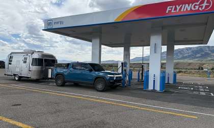 Blue Rivian R1T towing an Airstream travel trailer at a GM Energy Flying J charging station.