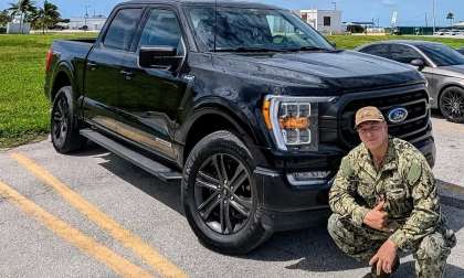 RJ posing beside his black 2022 Ford F-150 PowerBoost in military uniform.
