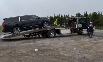 Saleh's 2023 GMC Yukon Denali Ultimate being loaded onto a flatbed tow truck on the roadside after experiencing a mechanical issue, with a person standing nearby during the recovery process.