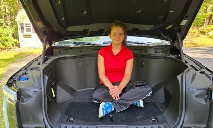 Image shows a young girls sitting inside of a Ford F-150 Lightning's frunk area