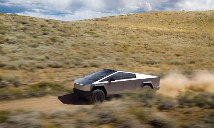 Tesla Cybertruck driving off road in desert kicking up dust trail
