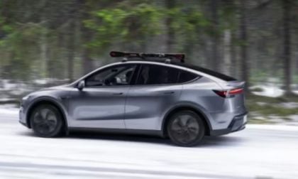 A Tesla Model Y is shown driving in a forest during winter