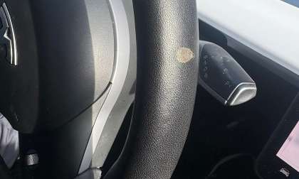 A defective Tesla steering wheel made from plastic vegan leather is shown peeling