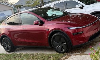 Red Tesla Model Y parked in residential driveway with suburban homes